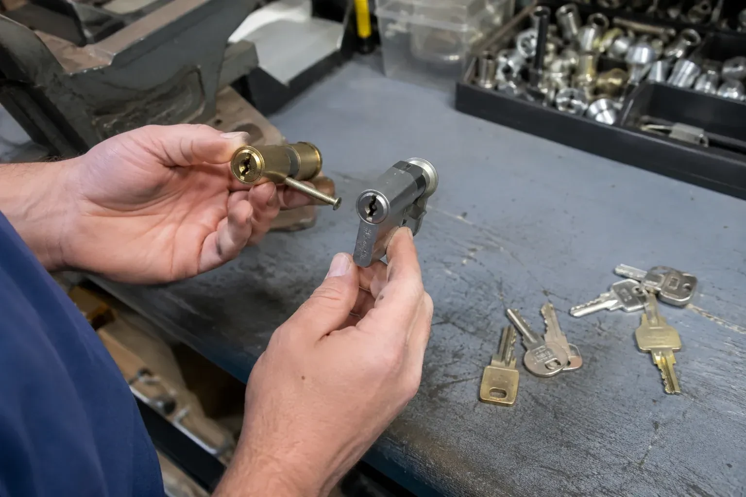 Hands comparing detached lock cylinders beside loose keys on a workbench. — Broken Key Extraction, Featherstone
