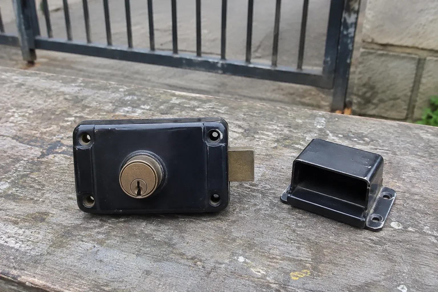 Detached rim gate lock and separate box keeper on an outdoor workbench. — Gate & Building Entry Locks, Haldimand County